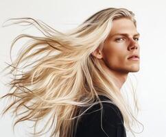 Young man showcases long blonde hair in studio setting while posing for a fashion photography session photo