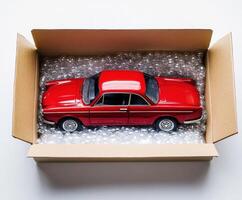 Detailed red toy car nestled in protective packaging inside a cardboard box ready for delivery photo
