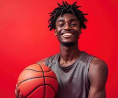 Young athlete smiles while holding a basketball against a vibrant red background photo