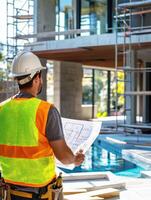Construction worker examining blueprints near a modern building site in daylight photo