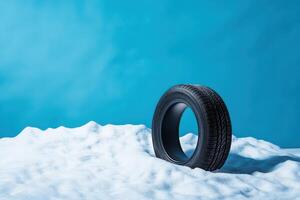 Black tire resting on white snow against a bright blue background creating a striking visual contrast photo