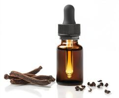 Essential oil bottle with dropper next to vanilla beans and cloves on white surface photo