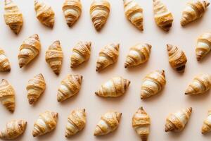 Fresh croissants arranged beautifully on a pastel peach background, emphasizing their flaky layers and golden crusts for bakery and breakfast themes photo
