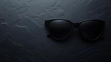 Stylish black sunglasses laid on a dark textured surface highlighting elegance and simplicity in design photo