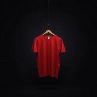 Red Tshirt Hanging on a Wooden Hanger Against a Black Background photo