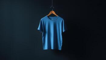 Blue TShirt Hanging on Wooden Hanger Against Dark Background photo
