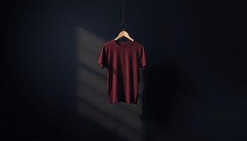 Maroon T-shirt Hanging on a Wooden Hanger Against a Dark Background photo