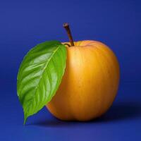 Golden Apple with Green Leaf on Blue Background photo