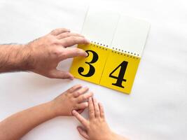 Father and child turn over page of calendar with large numbers photo