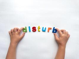 Colorful letters form the word disturb on white background with hands photo