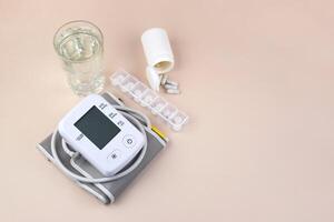 Pack of pills and a digital blood pressure tonometer on a light background with copy space. photo