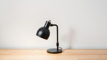 A black metal desk lamp with a simple adjustable arm on a light wood desk photo