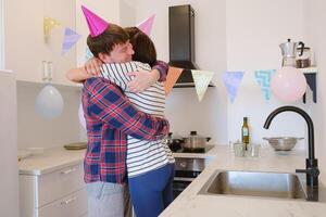 Young couple celebrates cozy birthday at home, enjoying cake and laughter in warm setting. joyful atmosphere, colorful decorations, and shared smiles. preparing for the holiday, decorating the room photo