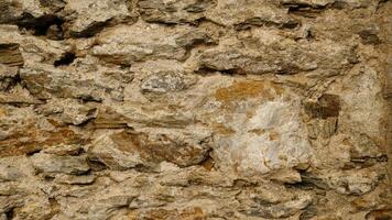 Texture of beige stone wall with rough masonry and uneven surface. Smooth, cracked surface. Old castle wall of stone different shape. Pattern with neutral colors. Minimal, stylish, trend concept. photo