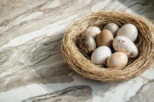Nestled among dried straw, a collection of eggs in earthy tones and speckled patterns creates a soft, organic display. A serene and harmonious representation of spring natural beauty photo