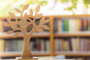 A wooden tree on a table in front of a bookcase photo