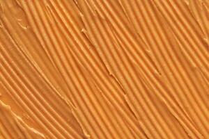 Smooth peanut butter texture with evenly spread creamy surface highlighting rich golden brown hue. photo