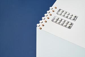 Assorted pills and tablets on white surface against blue background highlighting healthcare and medication. photo