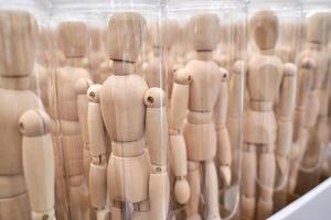 Wooden mannequins in containers displaying uniformity and repetition in art studio setting. photo