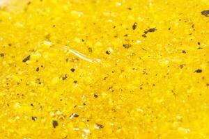 Close up of vibrant yellow slime with textured grains and shimmering surface. photo