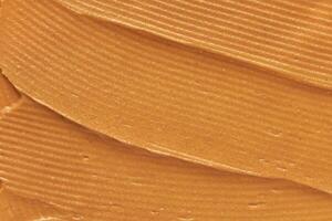 Close up of smooth peanut butter texture with natural brown color and creamy swirls. photo