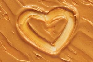 Heart shaped swirl in smooth creamy peanut butter spread for food and culinary arts concepts. photo