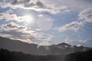 Serene mountain landscape with sunlight and clouds in the sky over misty forest. photo