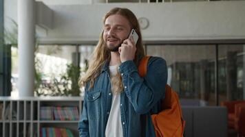 Happy pleasant conversation talk male in college academy university laugh fun talking Caucasian man guy student smiling laughing joy joyful speaking mobile phone call humorous studying education break video