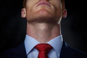 Close up of a mans neck and chin in a suit and red tie photo