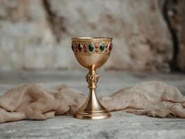 Ornate golden chalice with gemstones on rustic background photo