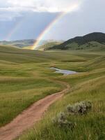 Double rainbow over a winding dirt road in a grassy valley photo
