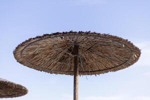 straw umbrellas on the beach close up photo