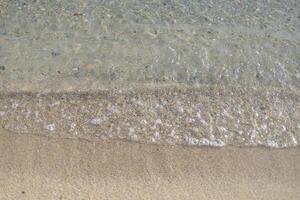 light foam of a sea wave on a sandy shore, top view photo