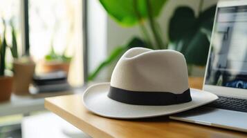 A hat sits on top of a laptop computer photo