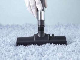 close up of gloved hand holding vacuum nozzle on soft, fluffy carpet, demonstrating effective cleaning. image conveys sense of cleanliness and care photo