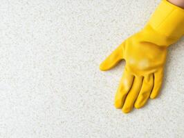 close up of yellow rubber glove resting on light textured surface, symbolizing cleanliness and protection. vibrant color adds cheerful touch to cleaning context photo