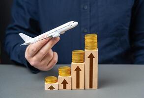 Airline profit growth. Increase in prices for tickets and flights. Loyalty programs and air miles, bonuses. Low cost airlines. Airplane on a growing stack of coins. photo
