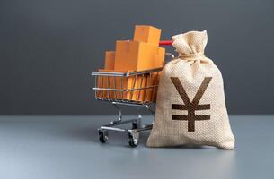 Shopping cart with boxes of goods and japanese yen money bag. Profit from the sale of goods. Start-up capital and equipment purchase. Marketing and market research. Purchasing power of buyers. photo
