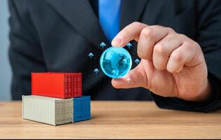 Businessman holding globe of planet Earth over stack of shipping containers. World trade and economic processes. Globalization. Import, export, transportation of goods and logistics. Production chains photo