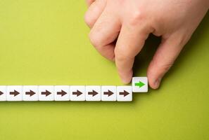 A hand makes a path out of blocks with arrows. The concept of moving forward and continuing progress. Strategic planning, forward momentum, and the continual pursuit of growth and improvement photo