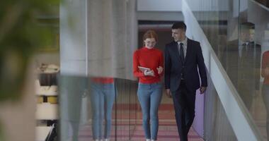 In the dynamic environment of a modern startup company, the director engages in a discussion with his young business colleague while they walk, reflecting the spirit of collaboration and innovation in video