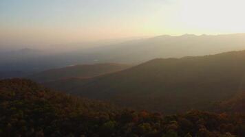 Beautiful sunset in the winter mountains. The setting sun shines down on a serene mountain landscape covered with tropical trees in the evening. video