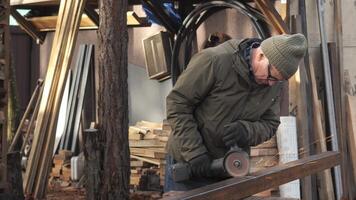 An artisan in a beanie works hard, cutting metal with sparks flying, surrounded by tools and wooden materials in the workshop courtyard. video