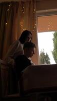 Quiet Moments of Comfort and Love A serene scene of a young couple by the window. The girl gently hugs the boy, creating an intimate moment of warmth and connection, with golden lights adding a video