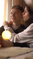 A young couple shares a playful moment, feeding each other slices of a tangerine. The warm lighting, glasses of wine, and bokeh of fairy lights create an atmosphere of intimacy and joy, highlighting video