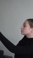 A dancer in a black open-back outfit moves gracefully against a neutral backdrop. The pose captures the elegance and focus of artistic expression, highlighting the beauty of fluid movement video