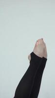 Close-up of a dancers pointed feet in black leggings, showcasing precision and elegance. The minimalist background highlights the strength and grace captured in the delicate movement video