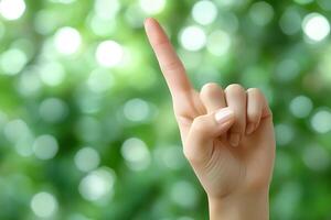 Gesturing Hand with Raised Index Finger Against Blurred Green Background for Communication Concepts photo
