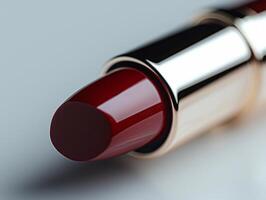 macro view captures rich red lipstick bullet featuring branded logo on tip. minimalist white backdrop emphasizes its luxurious design and pigmentation photo