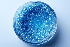 macro view reveals striking cobalt blue eyeshadow compact sparkling texture inside. clear container enhances vibrant color set against pure white background photo